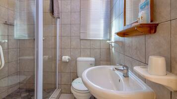 A bathroom with a shower, toilet, sink, and a towel rack.