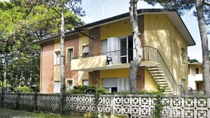 Un immeuble de deux étages avec une façade jaune, un balcon et un escalier menant à l’étage supérieur.
