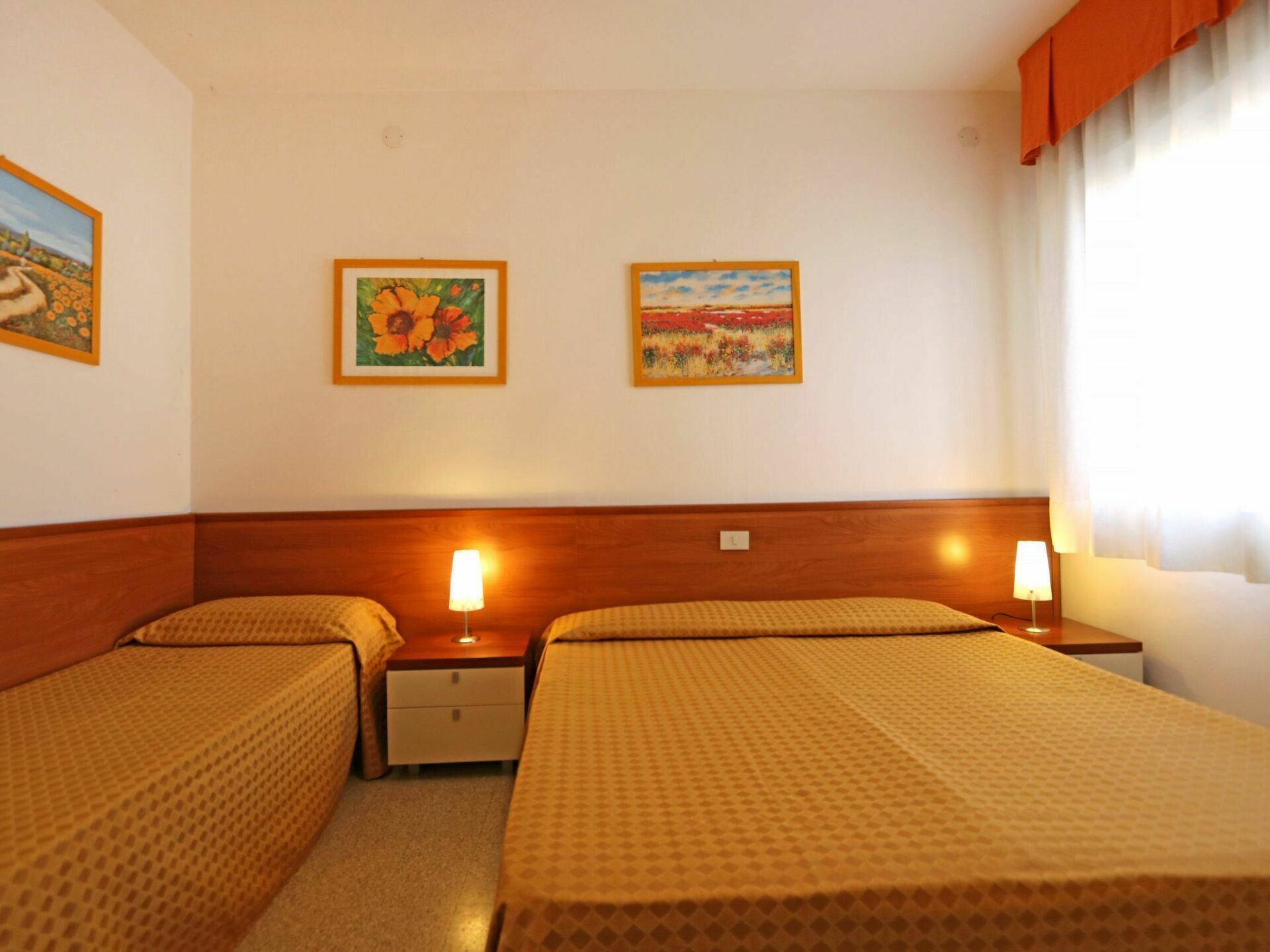 Ein Hotelzimmer mit zwei Betten, Holz-Kopfteilen und je einem Nachttisch.
