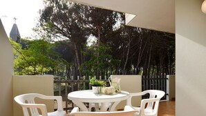 A patio with a round table and four white chairs, surrounded by a wooden fence and trees. - Cosy apartment for 5 guests with A/C, TV, balcony and pets allowed (San Michele Al Tagliamento)