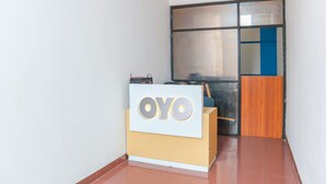 A reception desk with the logo "OYO" and a wooden counter. - OYO 2547 Assirot Residence (Jakarta)