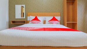 A neatly made bed with white and red bedding, a wooden headboard, and a wooden wardrobe to the right. - OYO 2547 Assirot Residence (Jakarta)