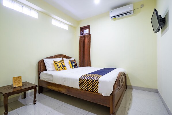 A neatly made bed with a wooden frame, a small bedside table, and a wall-mounted TV. - Hotel O Nabila Homestay (Ngaglik)
