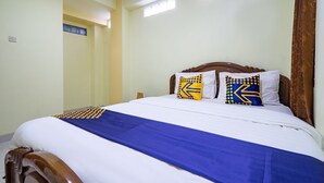 Een opgemaakt bed met een blauwe dekbedovertrek en twee kussens met geometrische patronen.