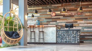 A modern bar area with a hanging chair, bar stools, and a stone wall with the text "7ROOMS". - 7Room Villa in central Seminyak | Private Pool & 7BR (Kabupaten Badung)