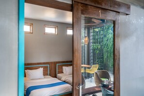 A room with two beds, a wooden headboard, a small table, and a chair.