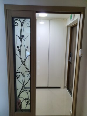 Un couloir étroit avec une porte en verre dépoli ornée d’un motif métallique décoratif.