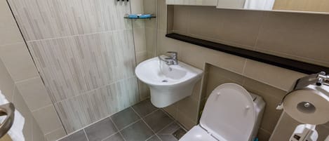 A bathroom with a bidet, toilet, and sink.