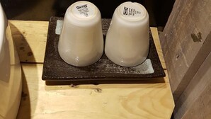 Twee witte keramische bekers op een houten dienblad.