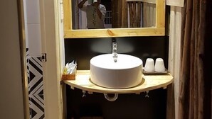 Een badkamer met een houten wastafelmeubel, een rond wastafel en een spiegel met houten lijst.