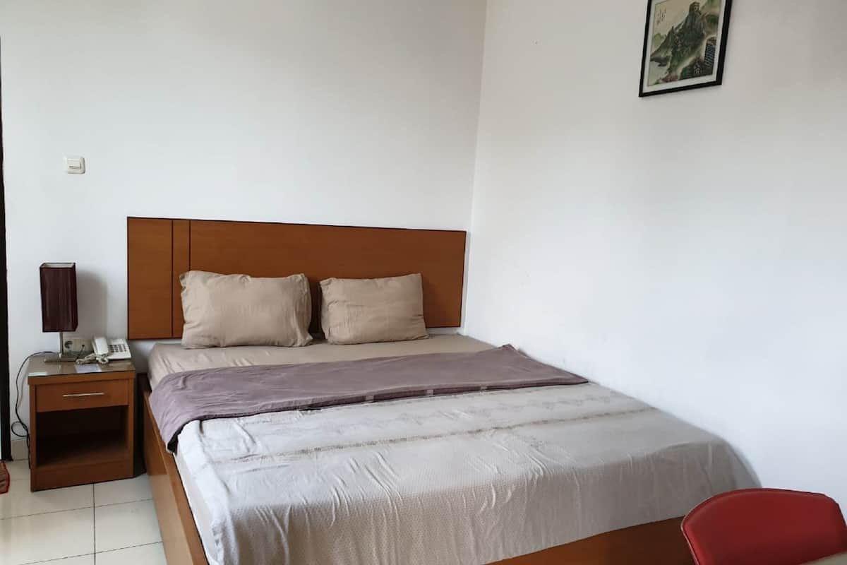 Une chambre d’hôtel comprenant un lit, une table de chevet, une lampe et un petit bureau avec une chaise.