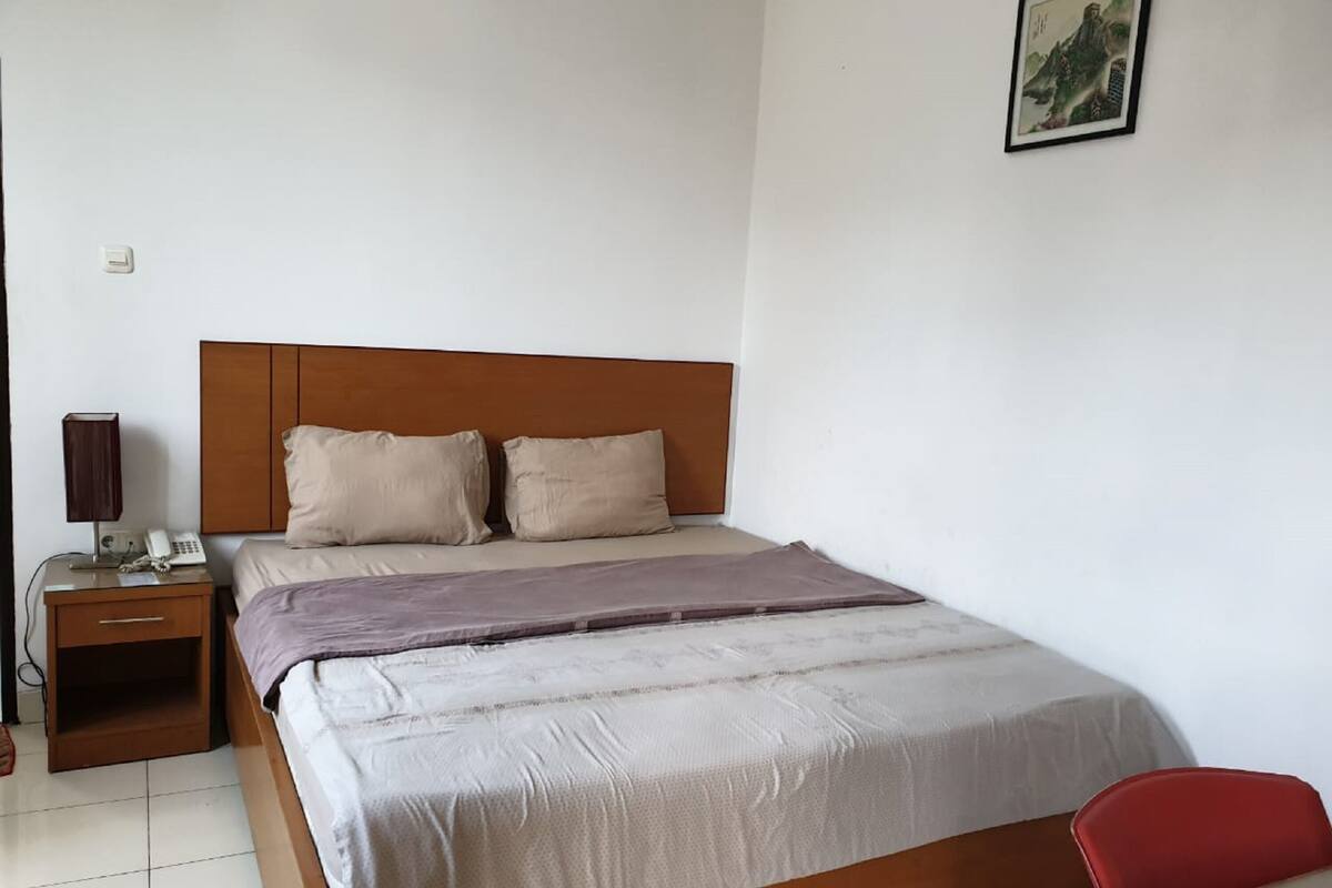 Une chambre d’hôtel avec un lit, une table de chevet avec une lampe, un téléphone et une petite table.