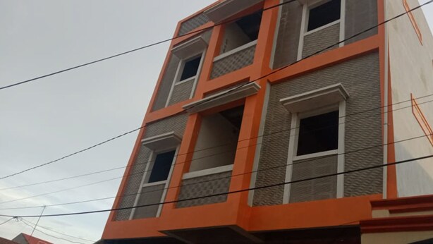 Ein mehrgeschossiges Gebäude mit modernem architektonischen Design, das Grau- und Orangetöne kombiniert.