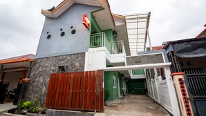 Ein zweistöckiges Haus mit einer Stein-Fassade, einem Holztor und einer grünen Tür.