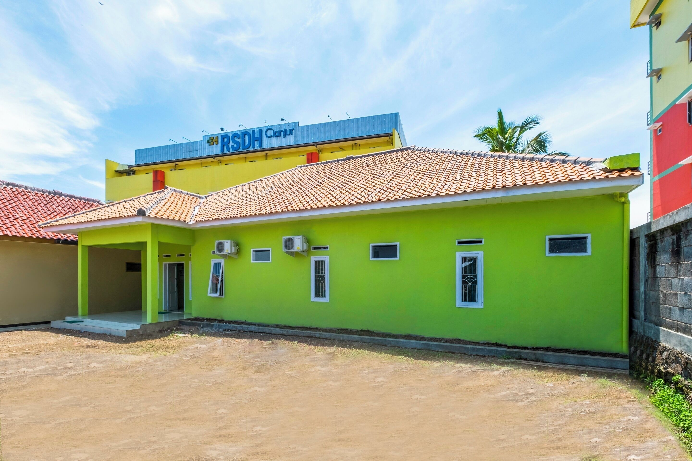 A building with a green facade and a tiled roof, featuring a sign that reads "RSDH Clinic."