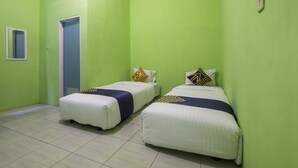 Una habitación con dos camas, cada una con un cojín azul y amarillo, y una puerta.