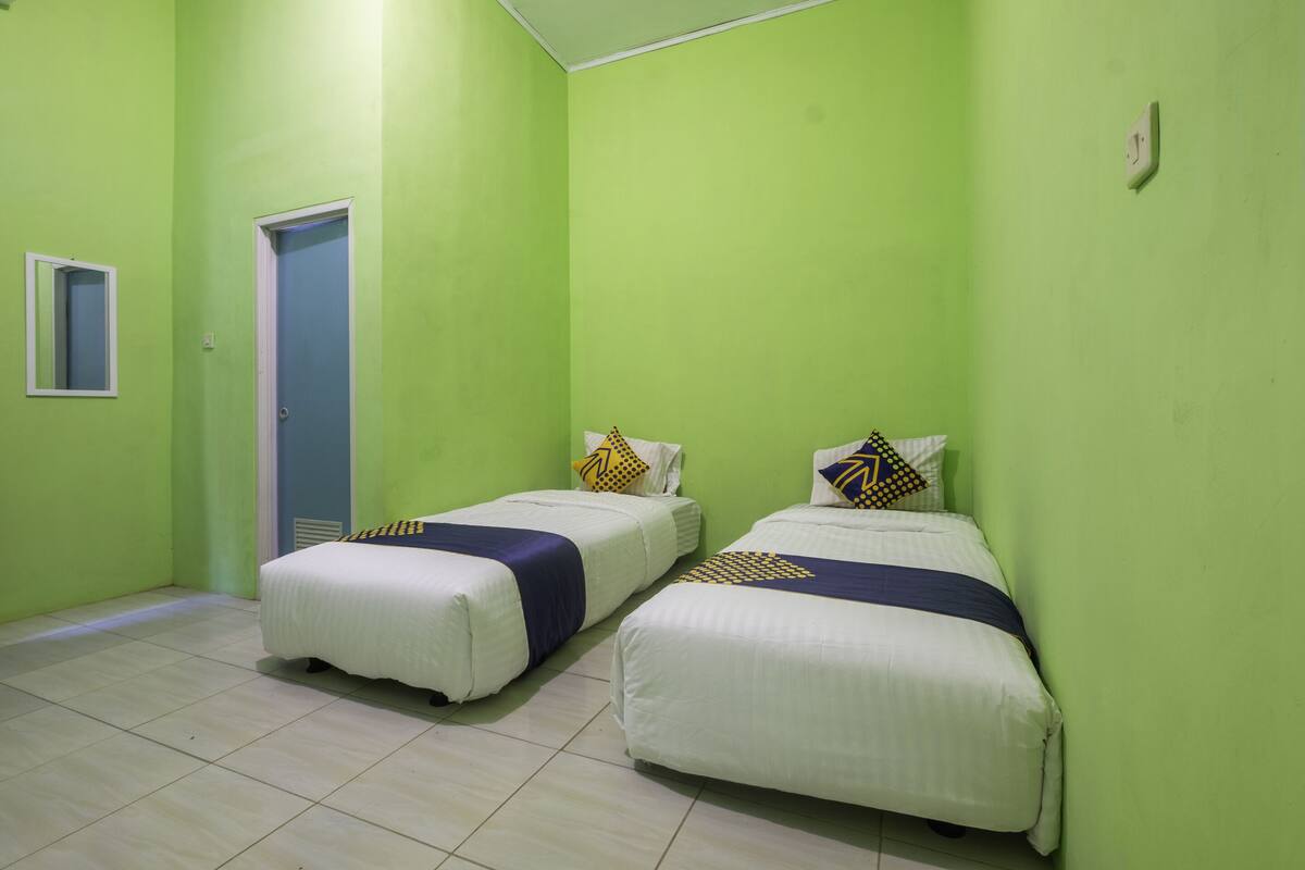 Een kamer met twee bedden, groene wanden en een deur.