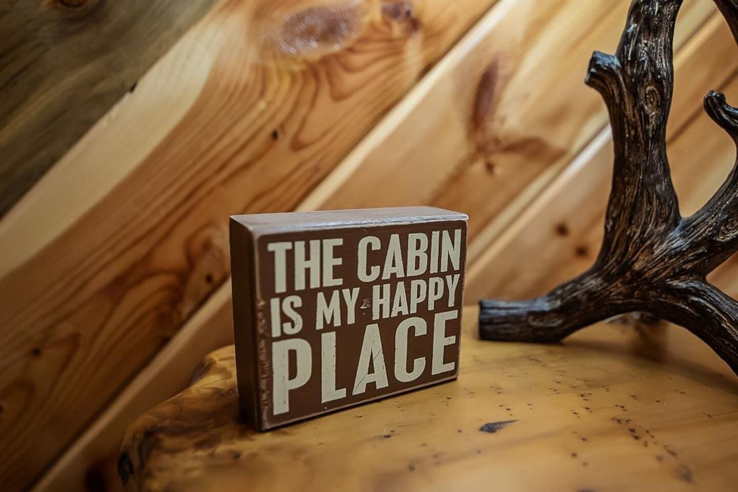 Het interieur van een houten blokhut, met een bord waarop staat: 'DEZE BLOKHUT IS MIJN HAPPY PLACE'.