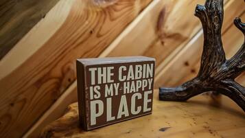 Het interieur van een houten blokhut, met een bord waarop staat: 'DEZE BLOKHUT IS MIJN HAPPY PLACE'.