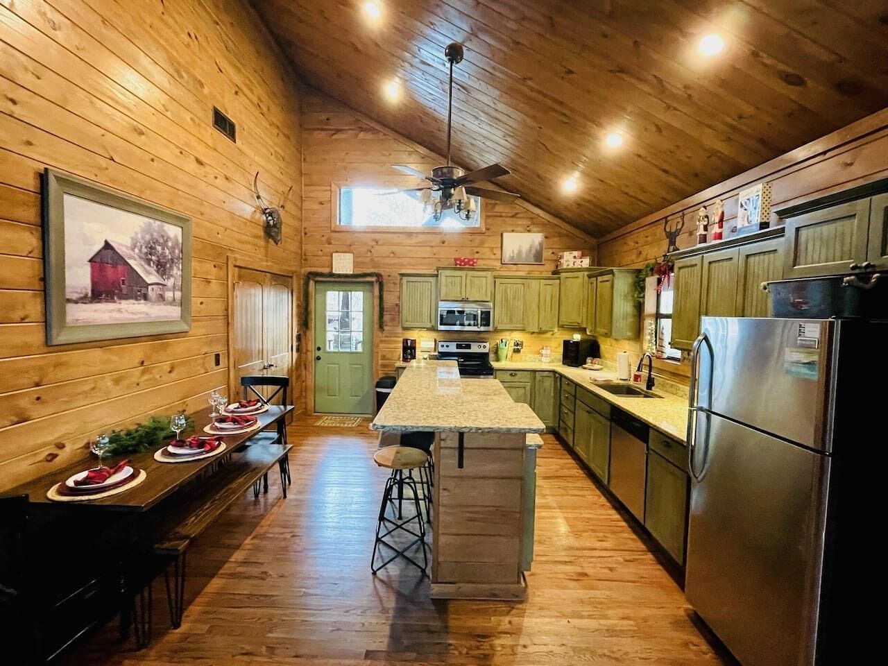 A wooden cabin interior with a kitchen, dining area, and a bar stool.