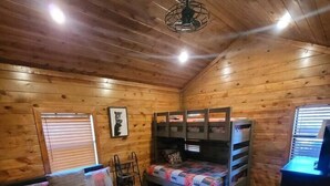 A cozy cabin-style bedroom with a wooden ceiling, a bunk bed, a single bed with a colorful quilt, a desk, and a chair. - Lake Ridge Retreat- Broken Bow/Hochatown- 2bd (Broken Bow)