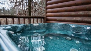 A hot tub with a wooden deck and a view of trees.