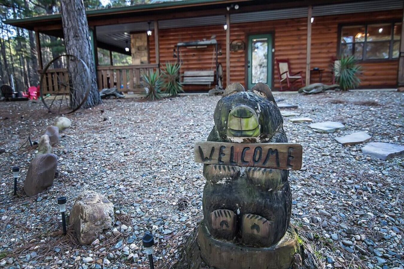 A rustic cabin with a wooden sign reading "WELCOME" in front.