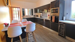 Una cucina moderna con isola centrale, elettrodomestici integrati e zona pranzo con sedie bianche.