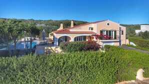 Una villa in stile mediterraneo con piscina, finestre ad arco e giardino.
