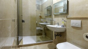A modern bathroom with a glass-enclosed shower, two sinks, a toilet, and a mirror above the sink. - Apartments Felicitas (Split)