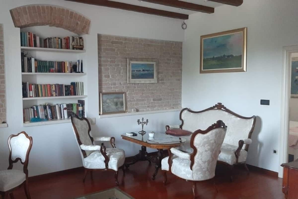 A room with a brick wall, a bookshelf, a dining table with chairs, and a sofa.
