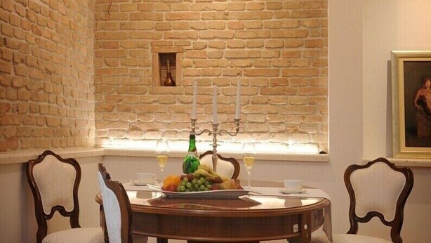 A dining area with a brick wall, a round wooden table, and four upholstered chairs. - Apartments Felicitas (Split)