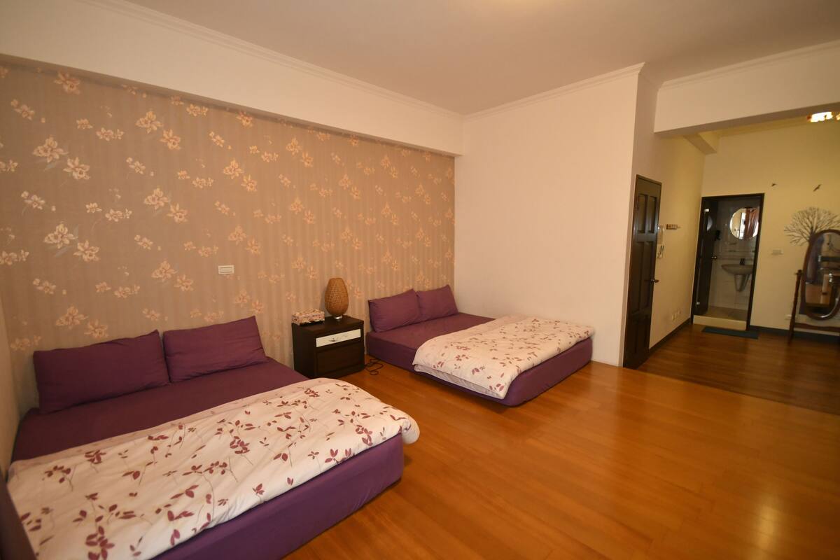 Een slaapkamer met twee bedden, houten vloeren en een behang met patroon.