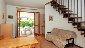 Ein Essbereich mit Holztisch und -stühlen, einer mit Blumenmuster bezogenen Couch und einer Treppe mit Holzstufen und schwarzen Geländern.