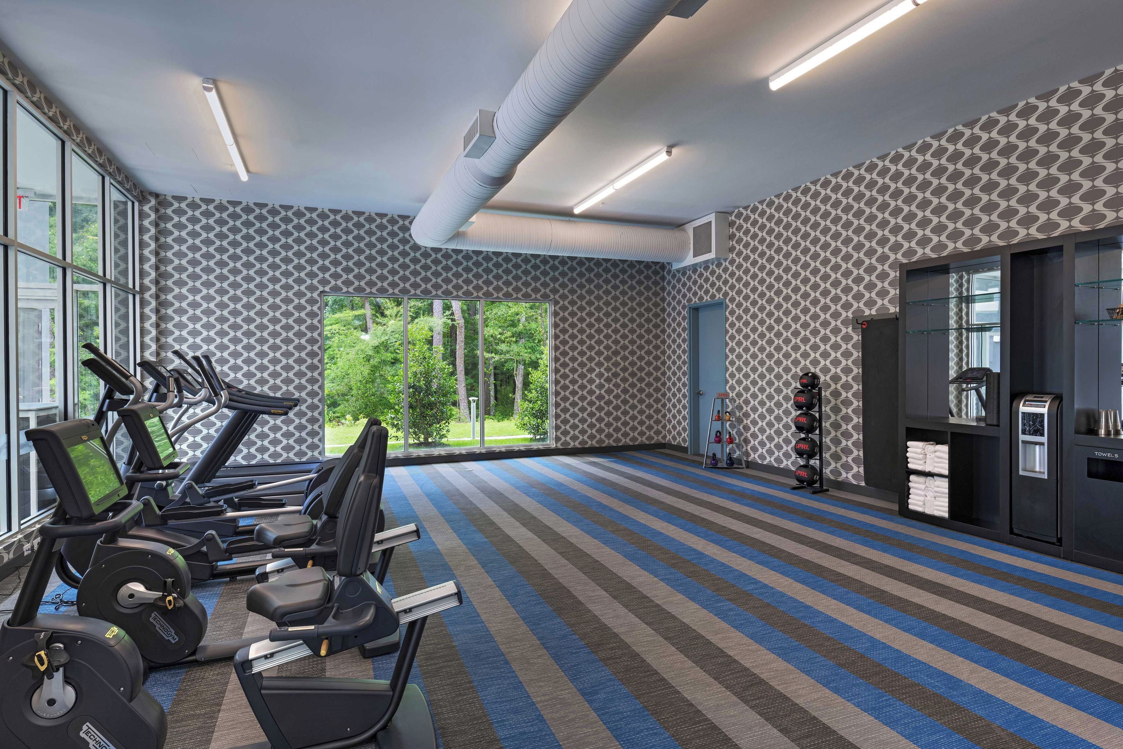 A gym with treadmills, weight machines, and a kettlebell rack.