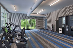 A gym with treadmills, weight machines, and a kettlebell rack.