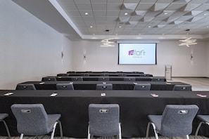 A conference room with a large screen displaying the logo of 'a loft hotels'.