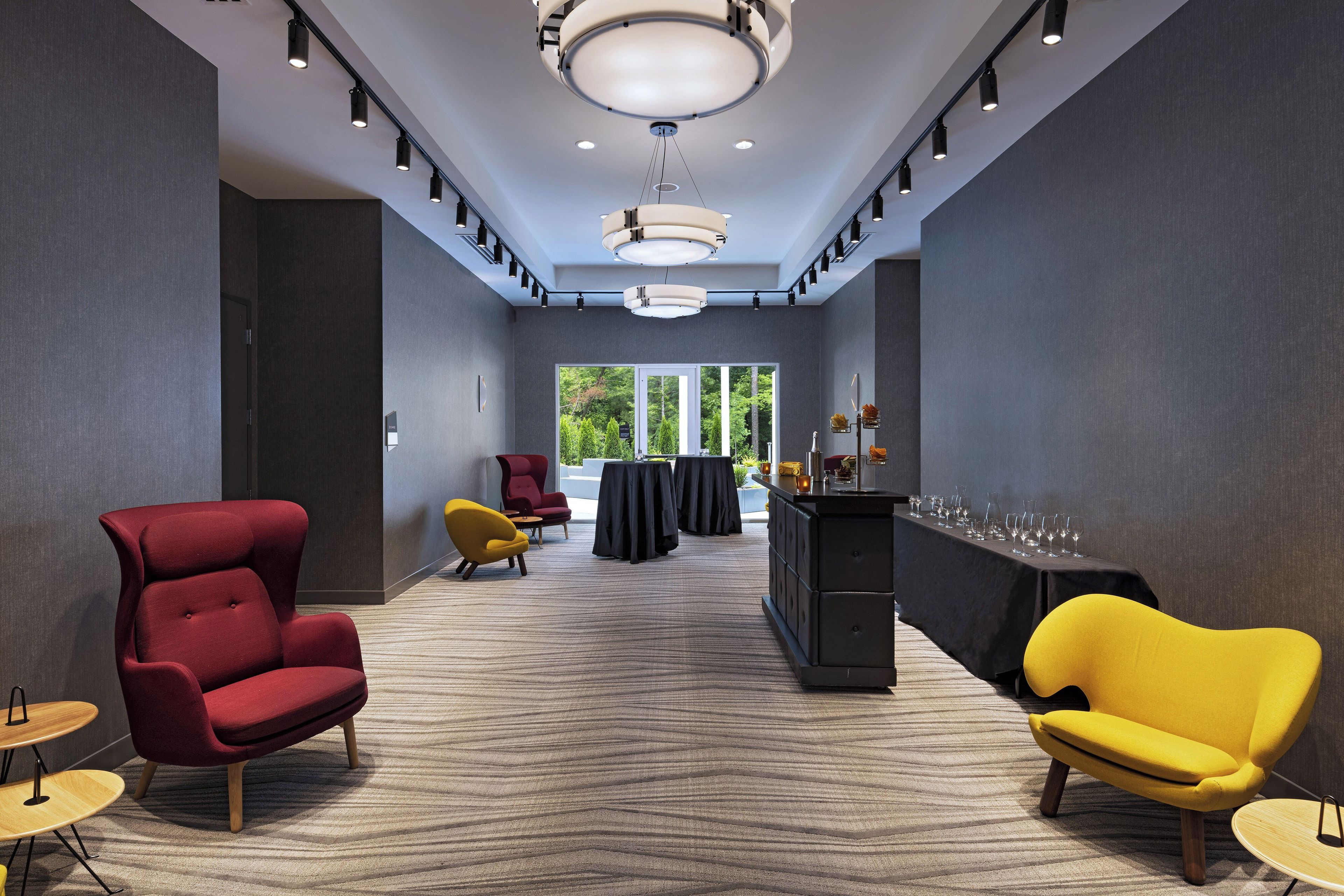 Un lobby moderno de hotel con un mostrador de recepción amplio, zona de estar y vistas a zonas verdes exteriores.