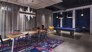 Une pièce moderne équipée d’une table de billard, d’une longue table avec des chaises et d’un tapis aux couleurs vives.