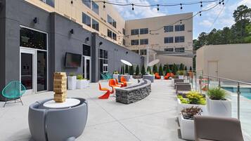 An outdoor seating area with modern furniture, a pool, and a building with multiple windows.