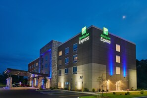 A Holiday Inn Express building with a modern design, featuring a stone facade and illuminated signage.