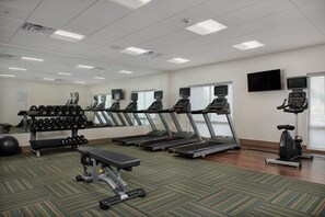Ein Fitnessstudio mit Laufbändern, Hanteln und Trainingsgeräten.