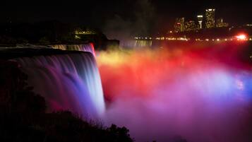 Una cascada de noche con el horizonte de una ciudad al fondo.