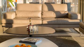 A modern living room with a beige leather sofa, a round coffee table, and a glass of red wine.