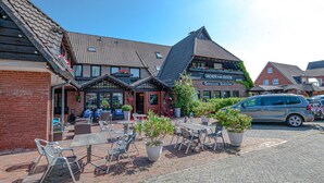 A restaurant with outdoor seating, a sign for 'Horn van Diek Restaurant', and a car parked nearby. - Nordseehotel Hörn van Diek (Esens)