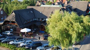 A hotel with a parking lot, outdoor seating area, and a view of the sea. - Nordseehotel Hörn van Diek (Esens)
