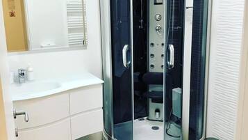 A modern bathroom with a glass-enclosed shower, a white sink, and a toilet.