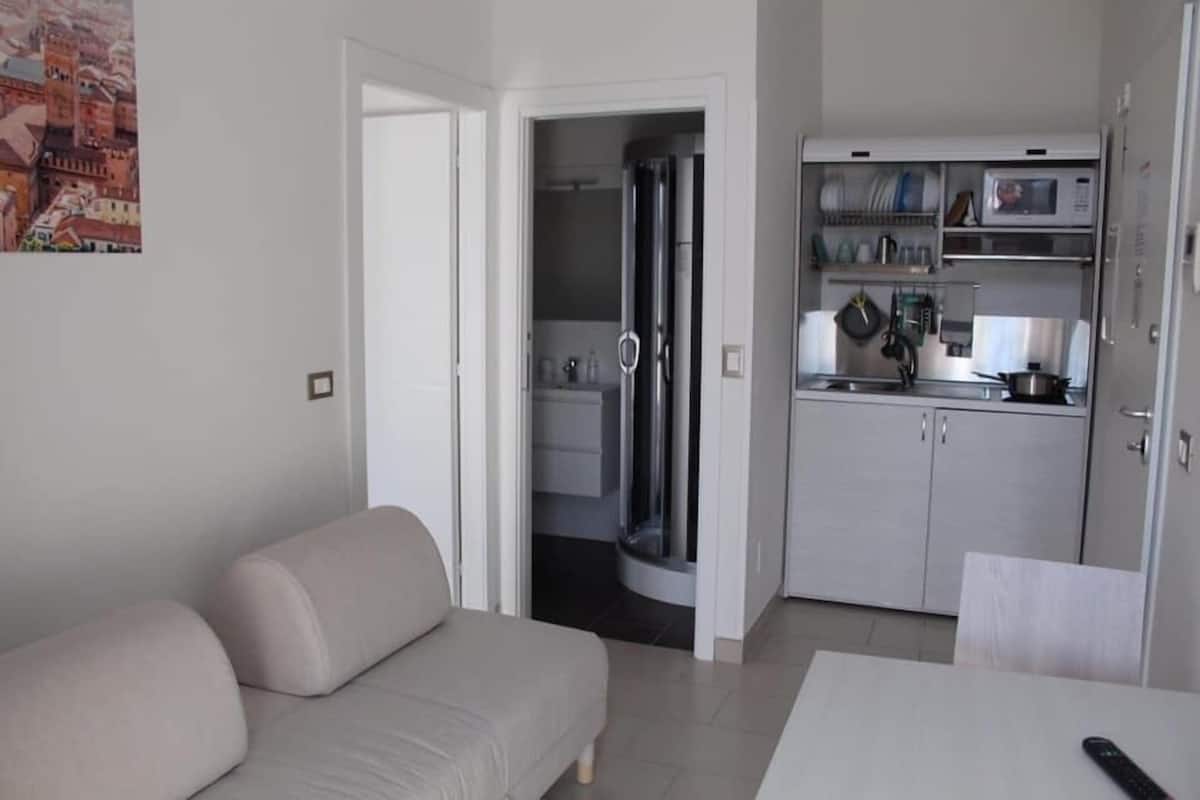 A compact living space with a sofa, a dining table, and a kitchen area including a microwave and cabinets.
