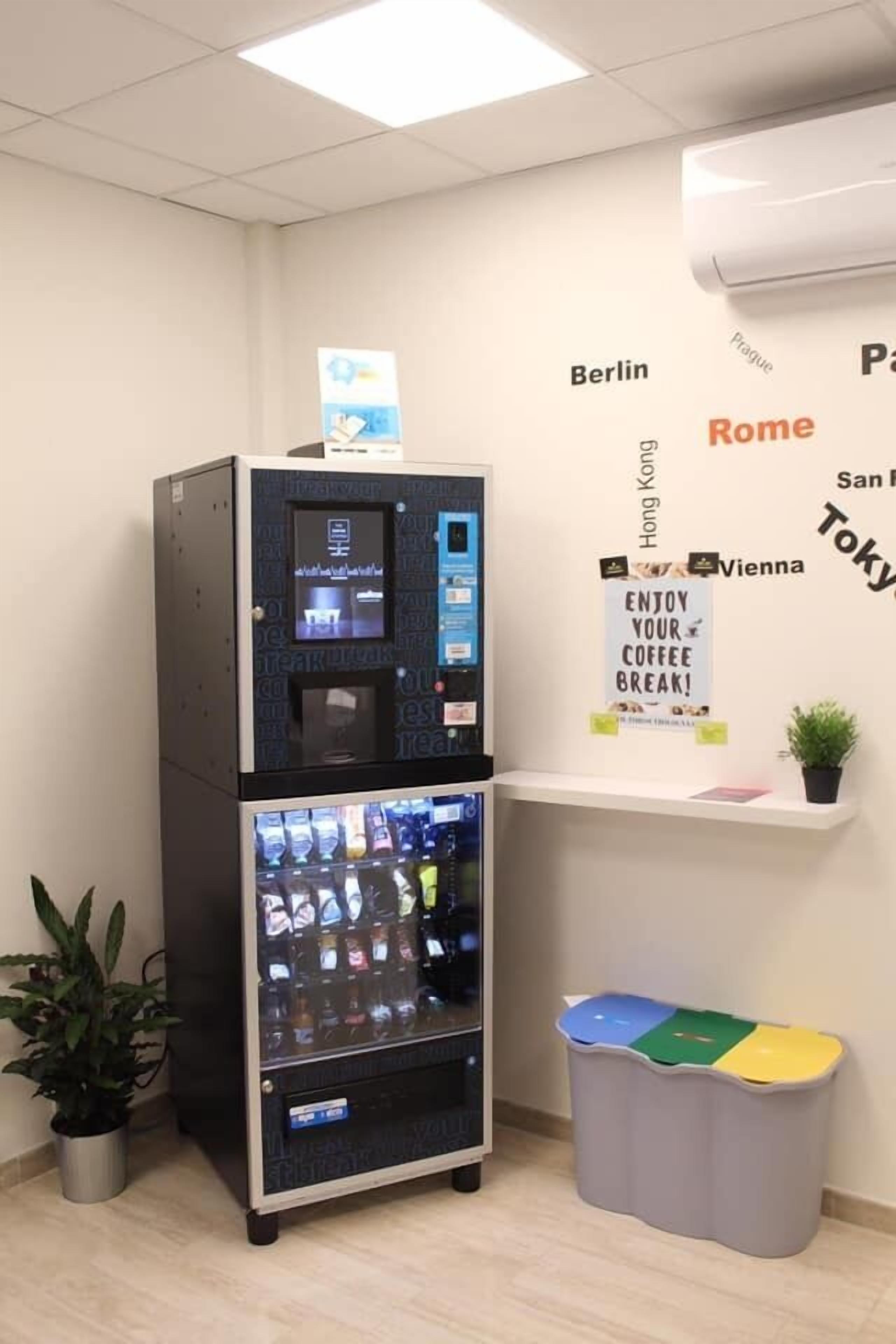 A vending machine with a coffee dispenser and a trash bin with color-coded sections.