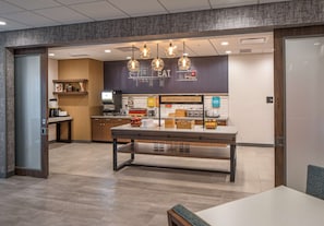 A modern kitchen area with a breakfast bar, hanging pendant lights, and a sign indicating breakfast service.